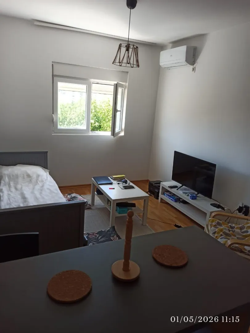 Namještena spavaća soba sa krevetom, radnim stolom i televizorom.