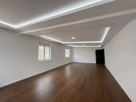 Prazna soba sa belim zidovima, drvenim podom i dekorativnim spuštenim plafonom sa rasvetom. - image 10