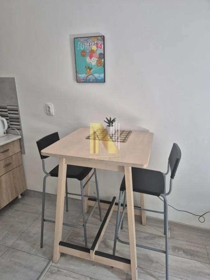 Trpezarijski sto sa visokim stolicama pored kuhinjskog dela.