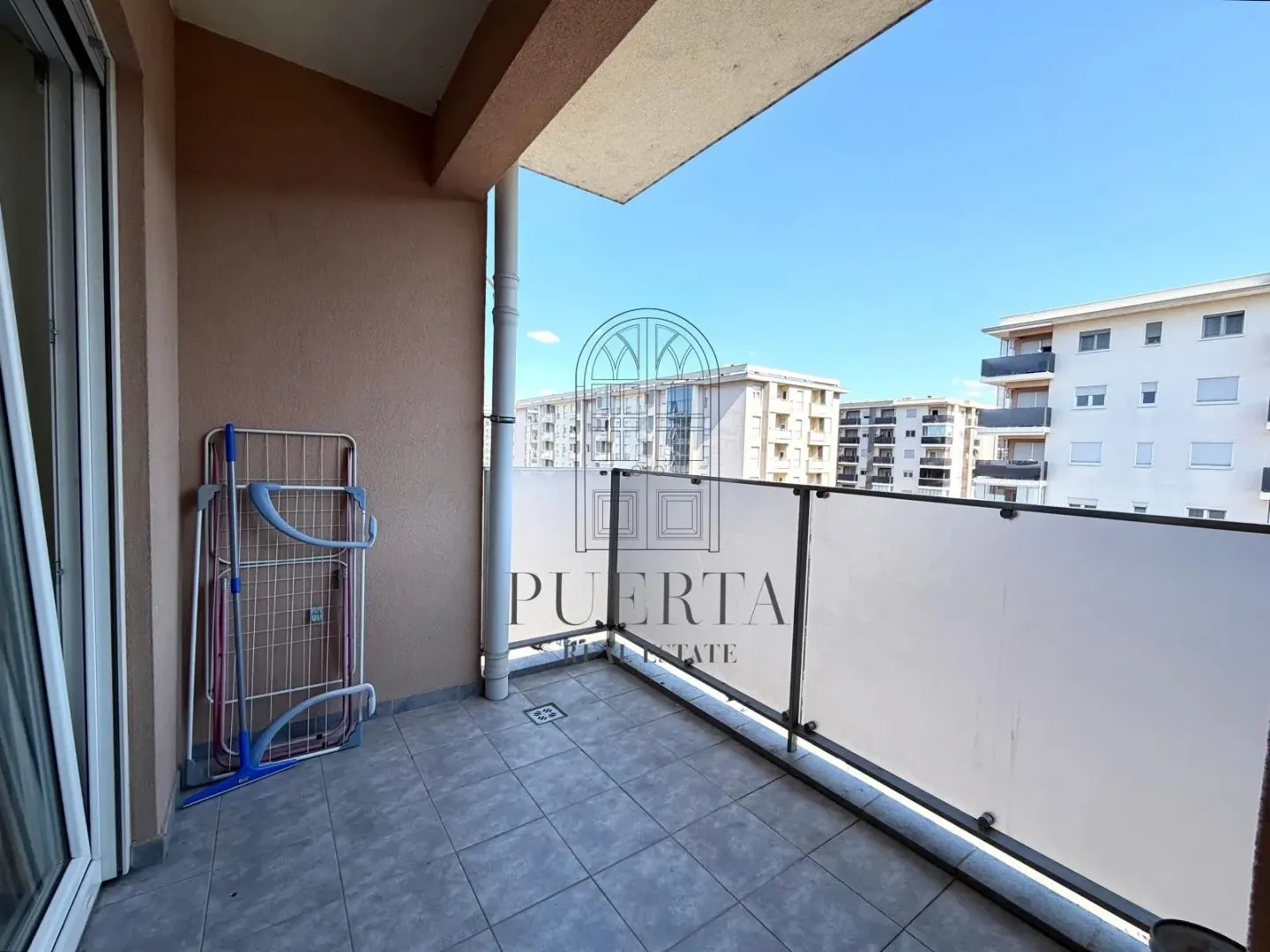 Covered balcony with tiled floor and view of the neighborhood.