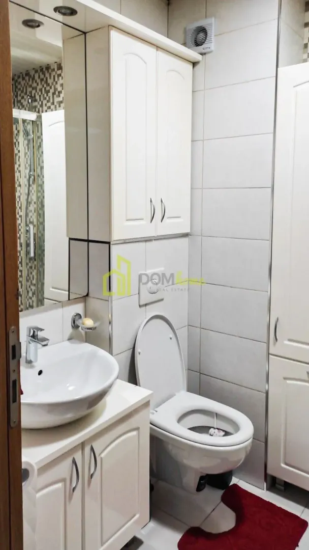 Smaller bathroom with a washbasin, toilet, cabinet, and shower enclosure.
