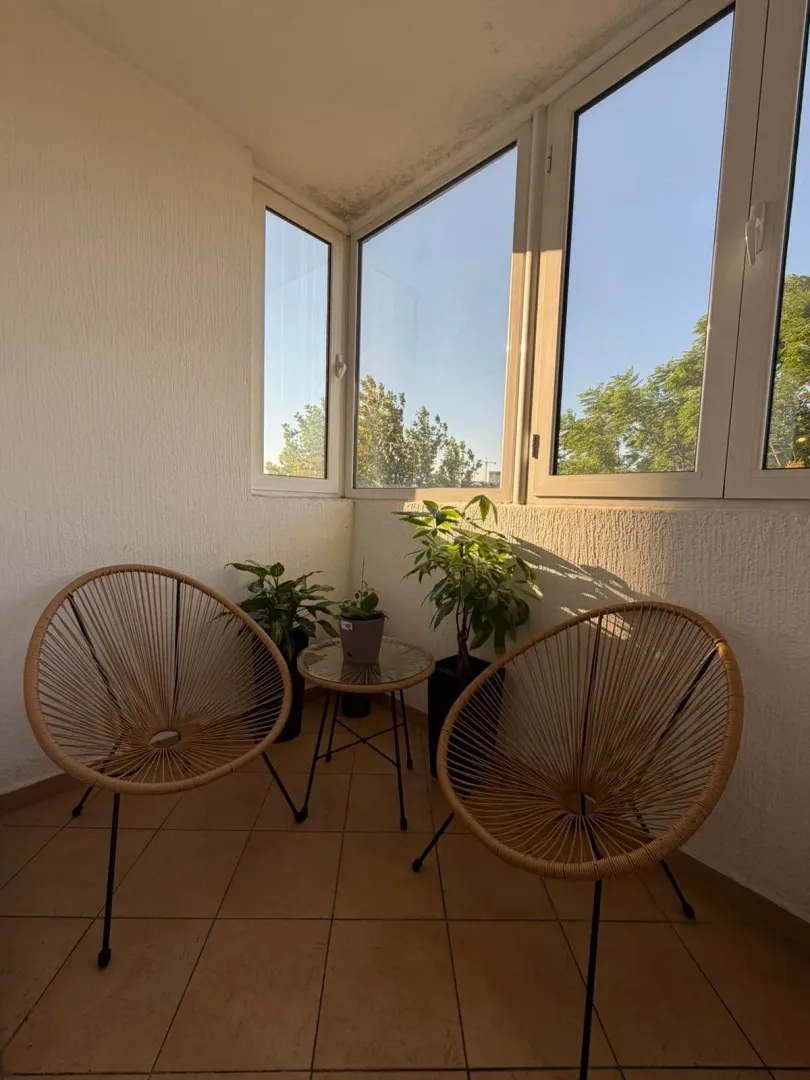 Zastakljena terasa sa garniturom za sjedenje i sobnim biljem.