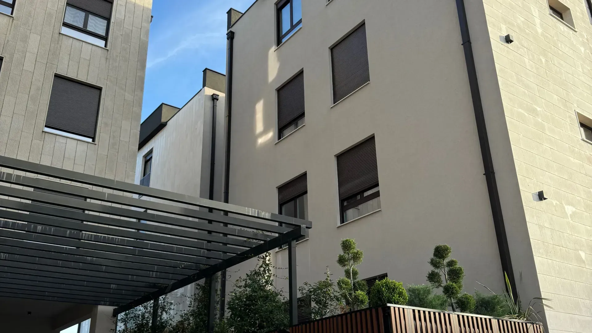 Pogled na spoljašnjost moderne stambene zgrade sa uređenim dvorištem.