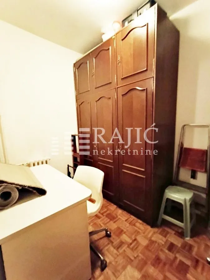 Small room with a wooden wardrobe, desk, and chair.