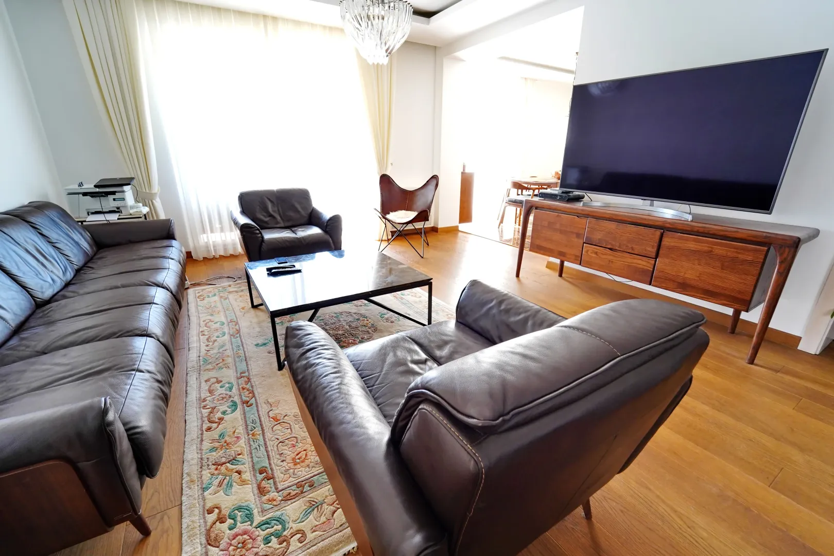 Spacious living room with leather sofas and a large TV.