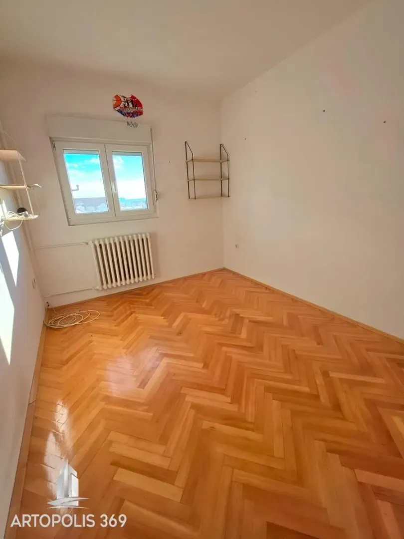 Prazna soba sa parketom i prozorom.