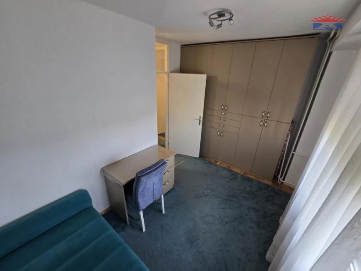 Bedroom with a bed, a desk, and a large built-in wardrobe.