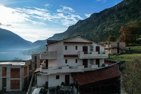 Pogled iz vazduha na spoljašnjost zgrade sa terasama u blizini mora i planina. - image 4