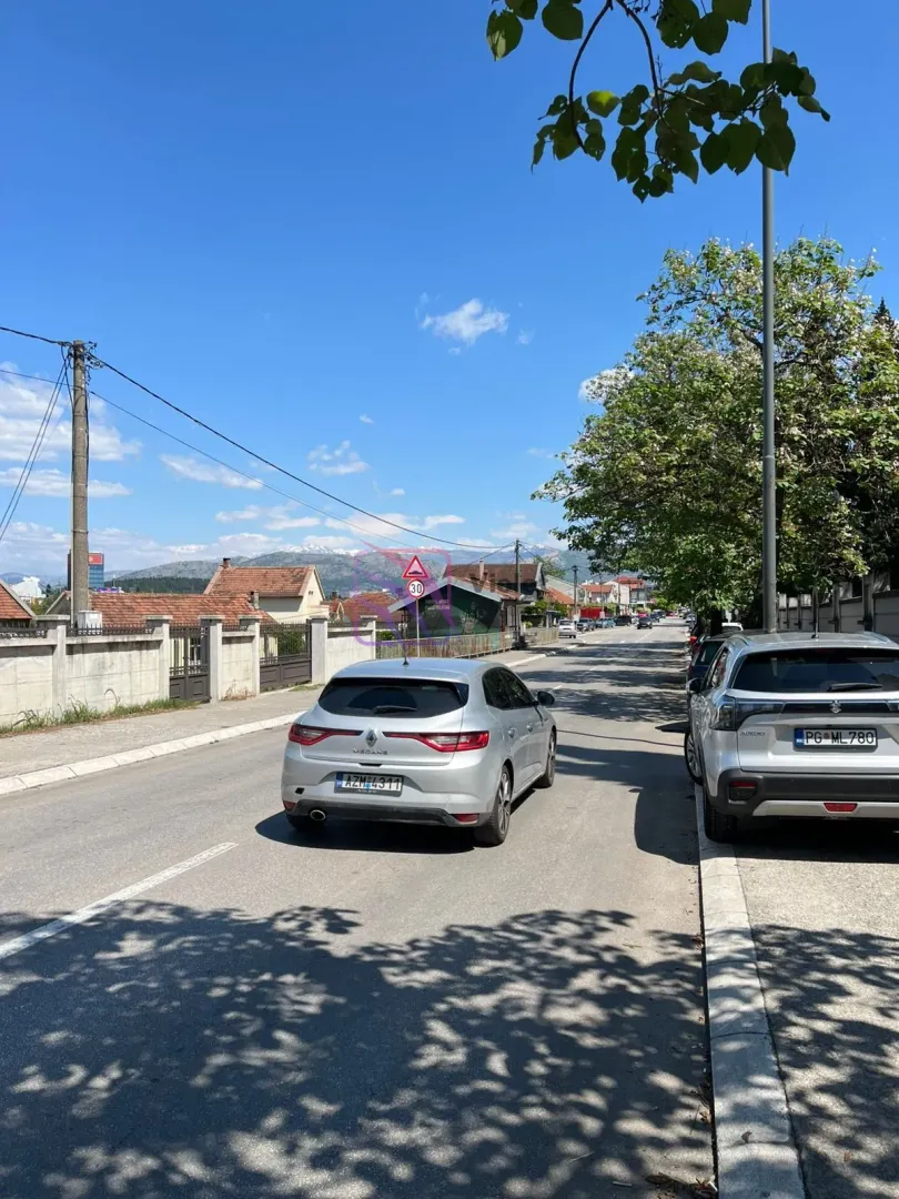 Pogled na ulicu ispred nekretnine sa parkiranim automobilima.