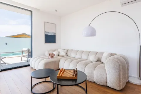 Living room with a comfortable sectional sofa, coffee table with a chess set, and access to a terrace with a pool. - image 16