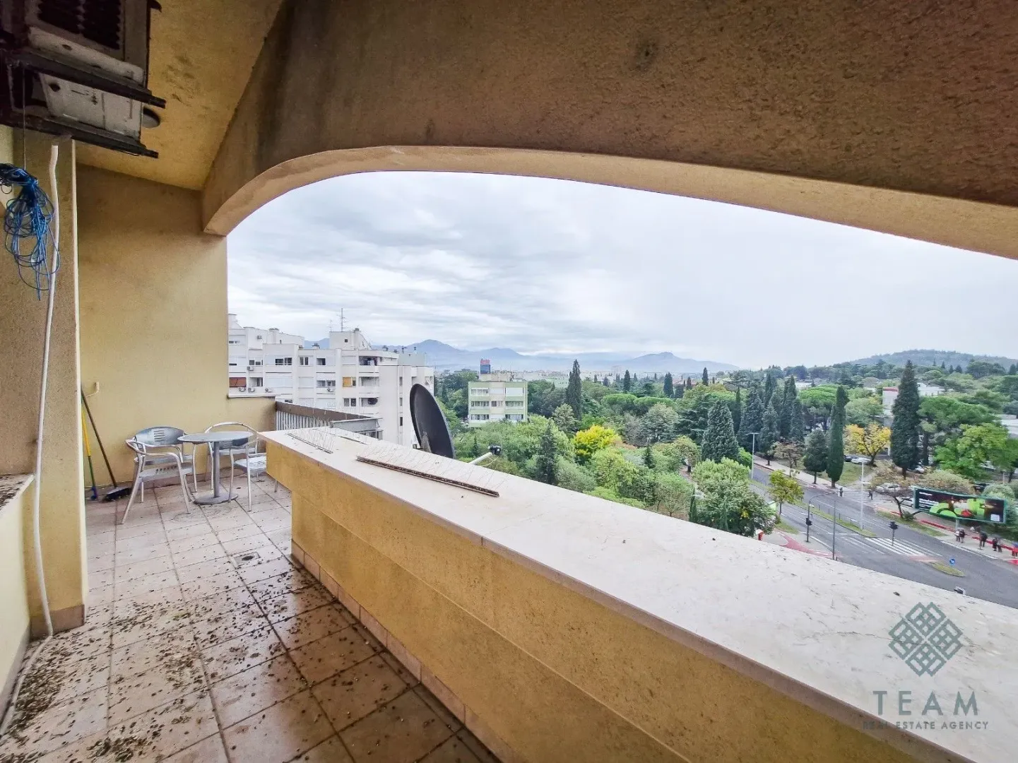 Covered balcony space with seating furniture and a city view.