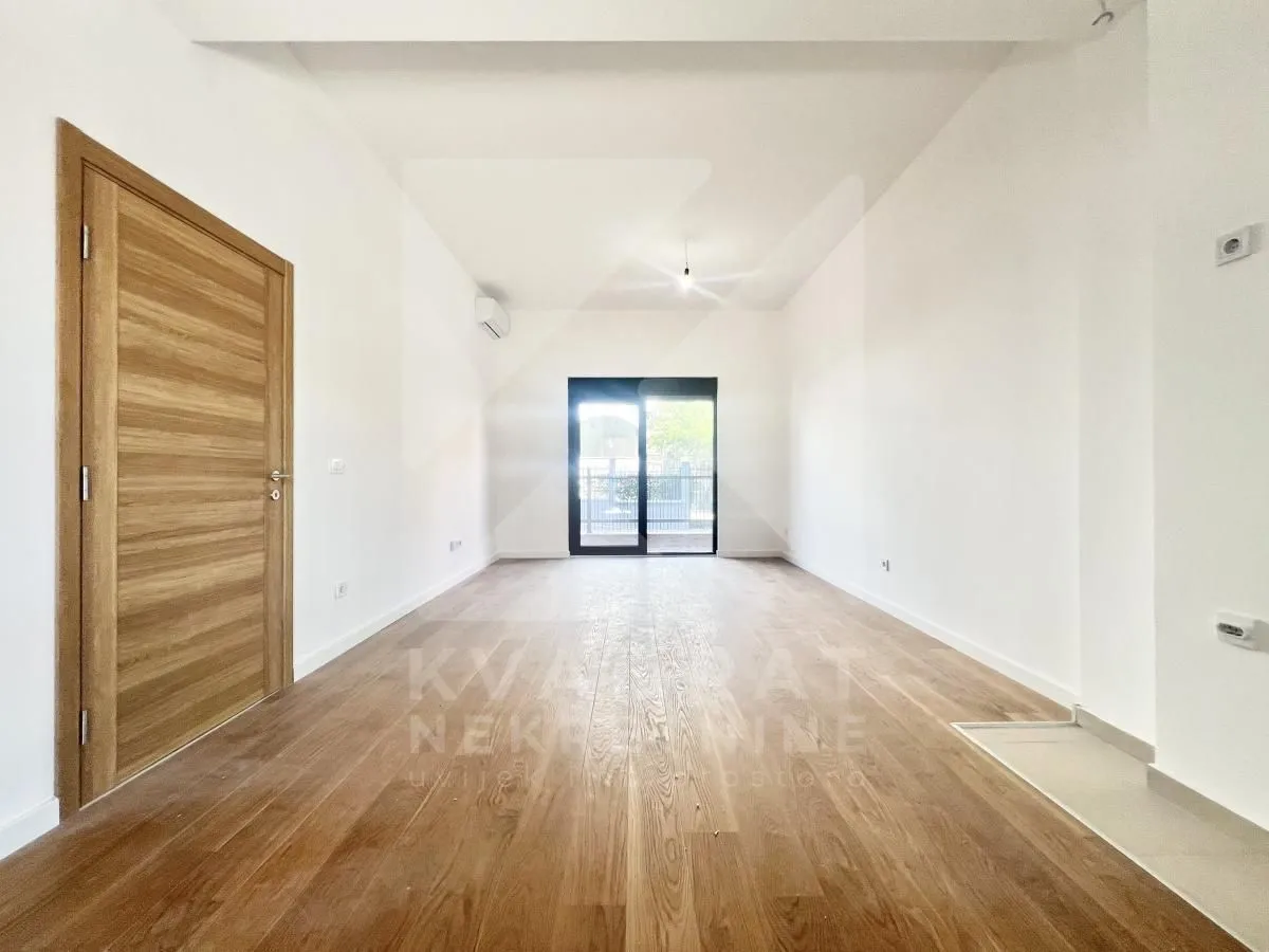 Empty bright room with wooden flooring and a door.