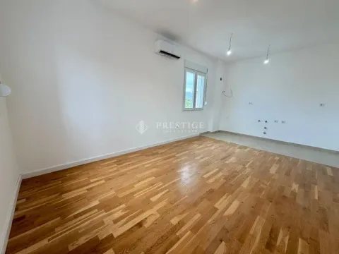 Prazna prostorija sa drvenim podom, bijelim zidovima i klima uređajem. - image 3