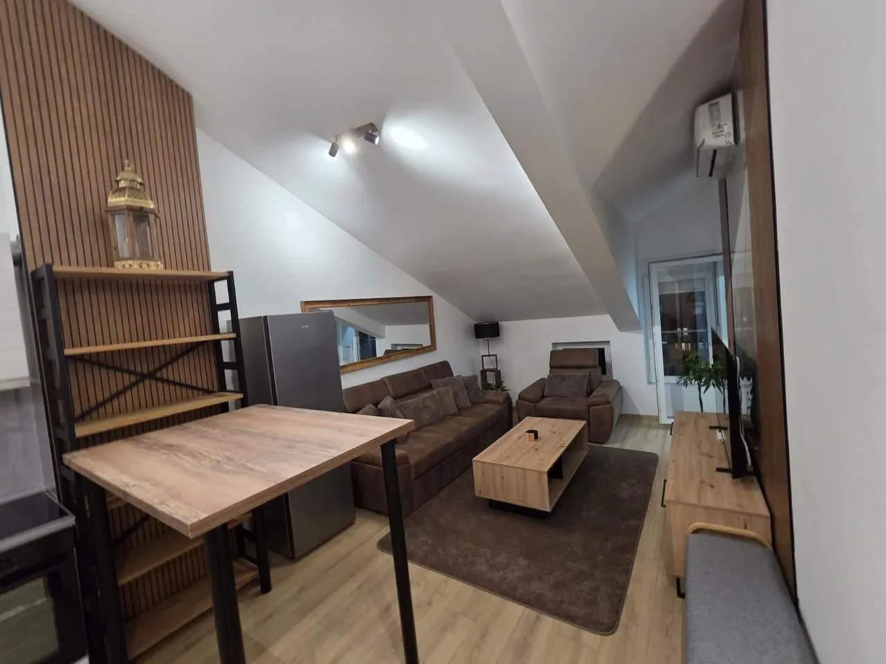 Living room with sofa set, dining table and kitchen elements in the attic.