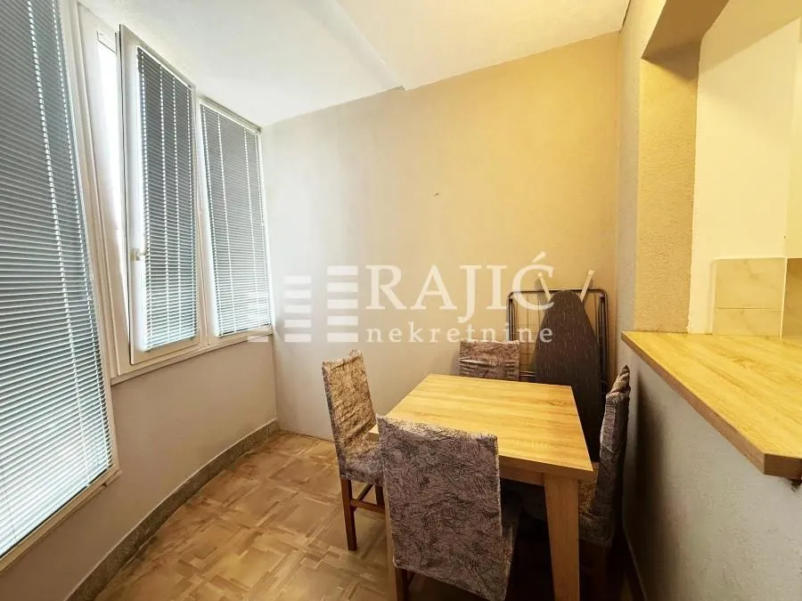Small dining area with a table, chairs, and windows with blinds.