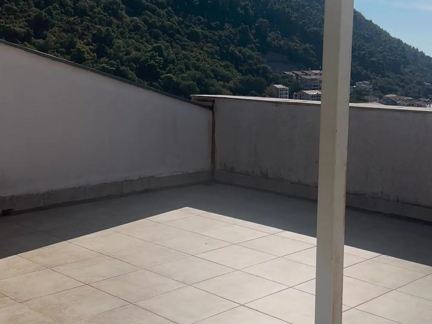 Empty tiled terrace with a hill view.