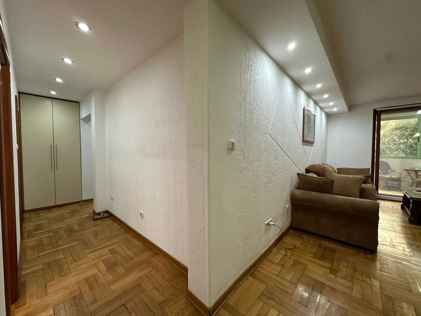 Living room with parquet flooring, furniture, and access to the terrace.