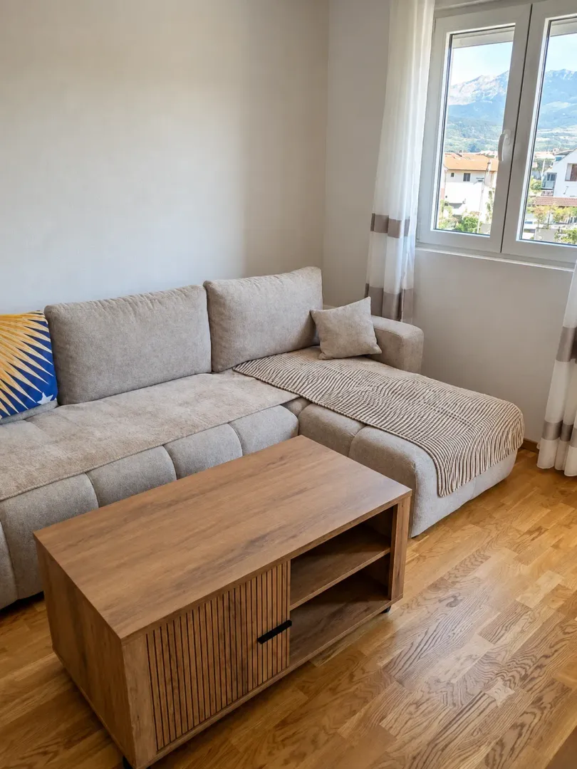 Living room with a sectional sofa, wooden coffee table, and a window with a mountain view.