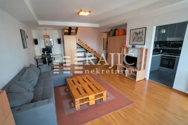 Spacious living room with a sofa and coffee table, overlooking the kitchen.