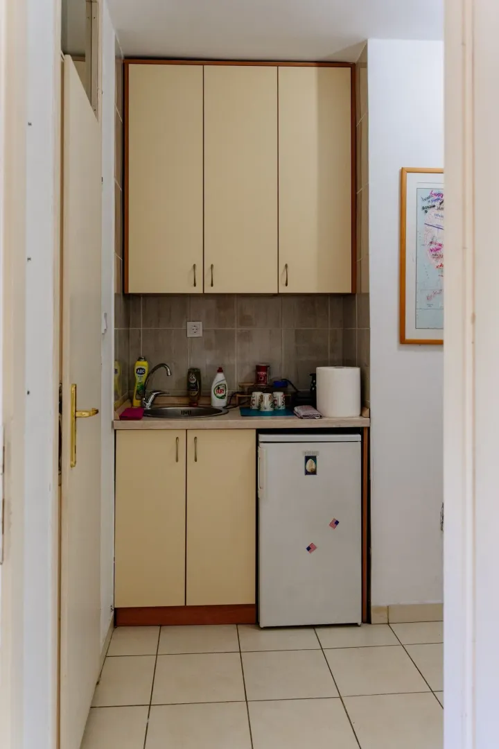 A small kitchenette with light cabinets and a mini fridge.