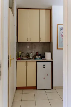 A small kitchenette with light cabinets and a mini fridge. - image 7