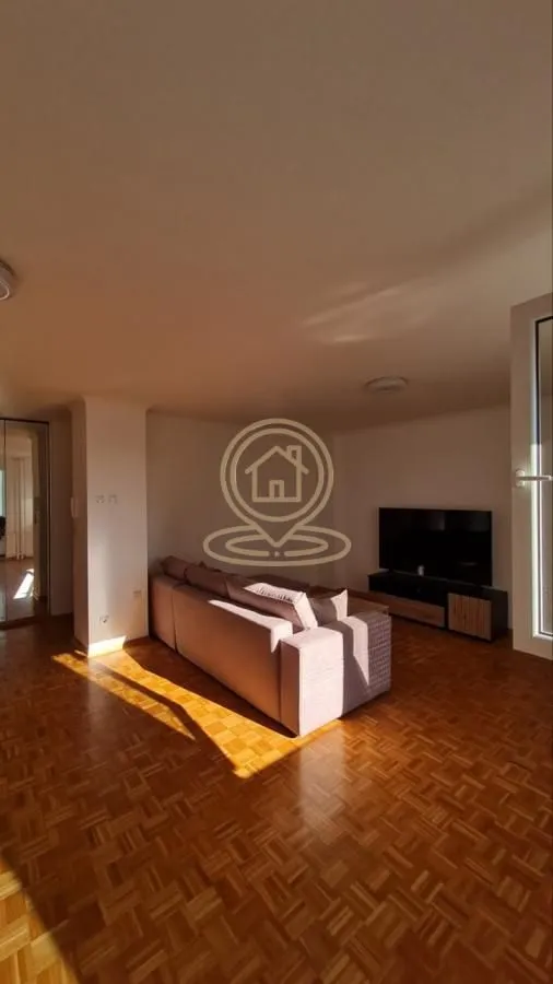 Living room with a corner sofa, television, and parquet flooring.