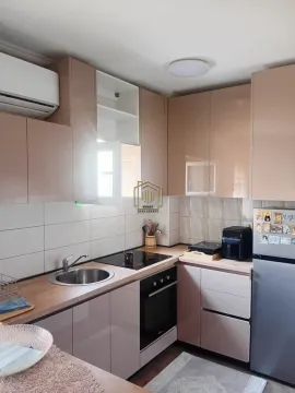 Compact kitchen with glossy cabinets, sink, and built-in appliances. - image 8