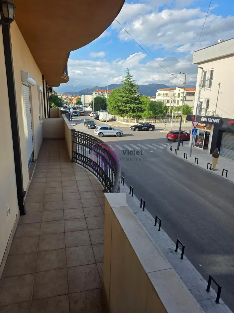 Dugi popločani balkon sa pogledom na ulicu i okolne zgrade.