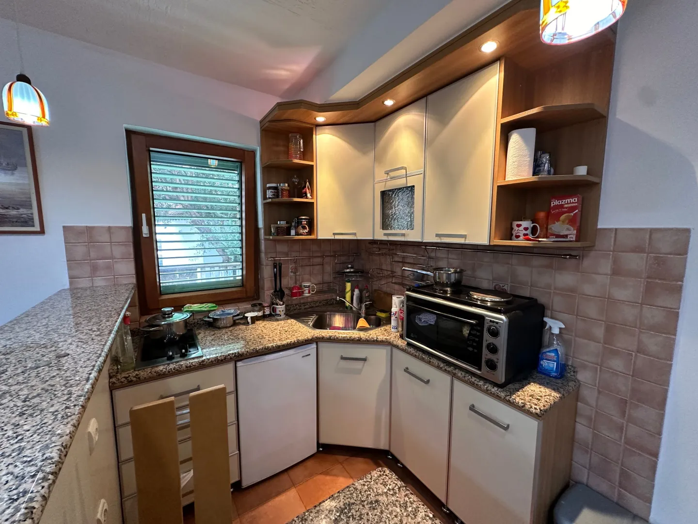 Smaller equipped kitchen with work units, sink and appliances.