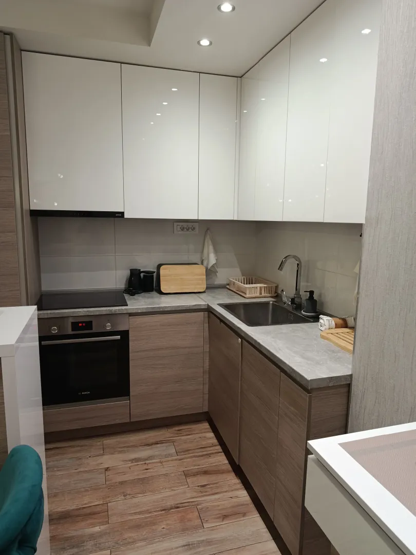 Modern kitchen with white upper cabinets and wooden lower cabinets.