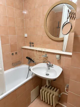 Kupatilo obloženo narandžastim pločicama sa kadom, umivaonikom i okruglim ogledalom. - image 13