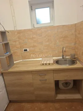 Smaller kitchen with a sink and wooden-pattern lower cabinets. - image 5