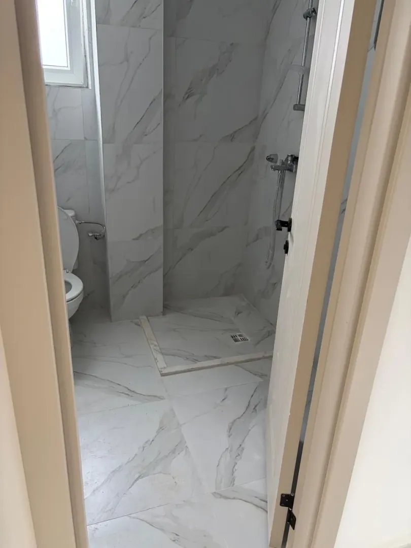 View of a modernly decorated bathroom with light marble tiles.