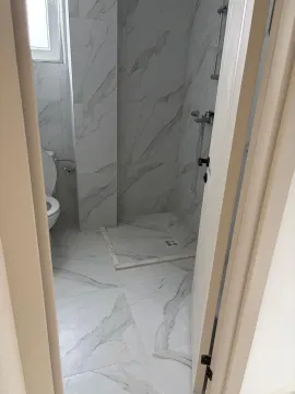 View of a modernly decorated bathroom with light marble tiles. - image 12