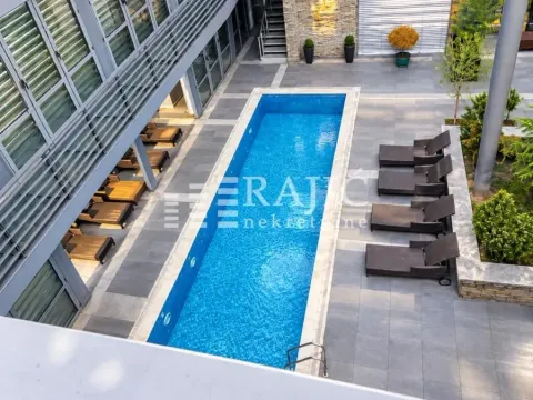 High-angle view of an outdoor swimming pool with loungers and a tiled building courtyard. - image 9