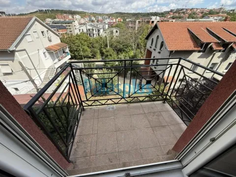 Manji popločani balkon sa crnom metalnom ogradom i pogledom na naselje. - image 9