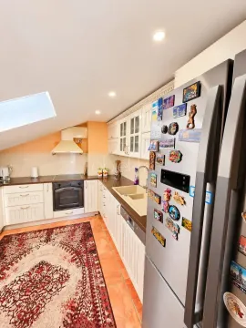 Attic kitchen with white cabinets, large refrigerator, and a rug on the floor. - image 10