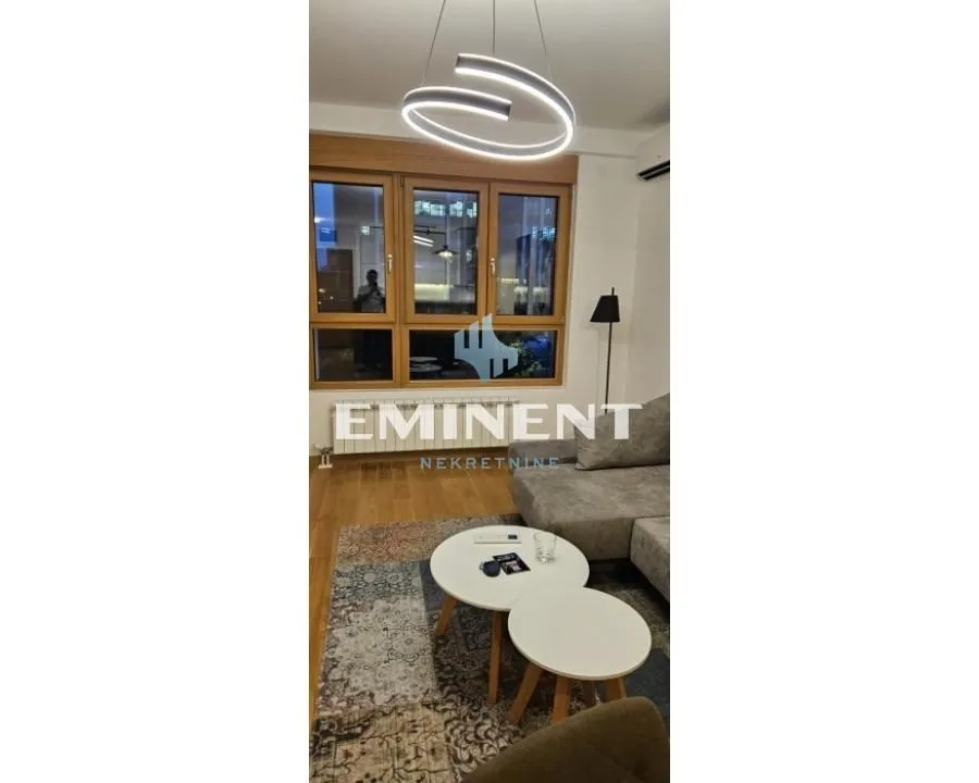 Dnevna soba sa garniturom, stočićima i modernim lusterom.