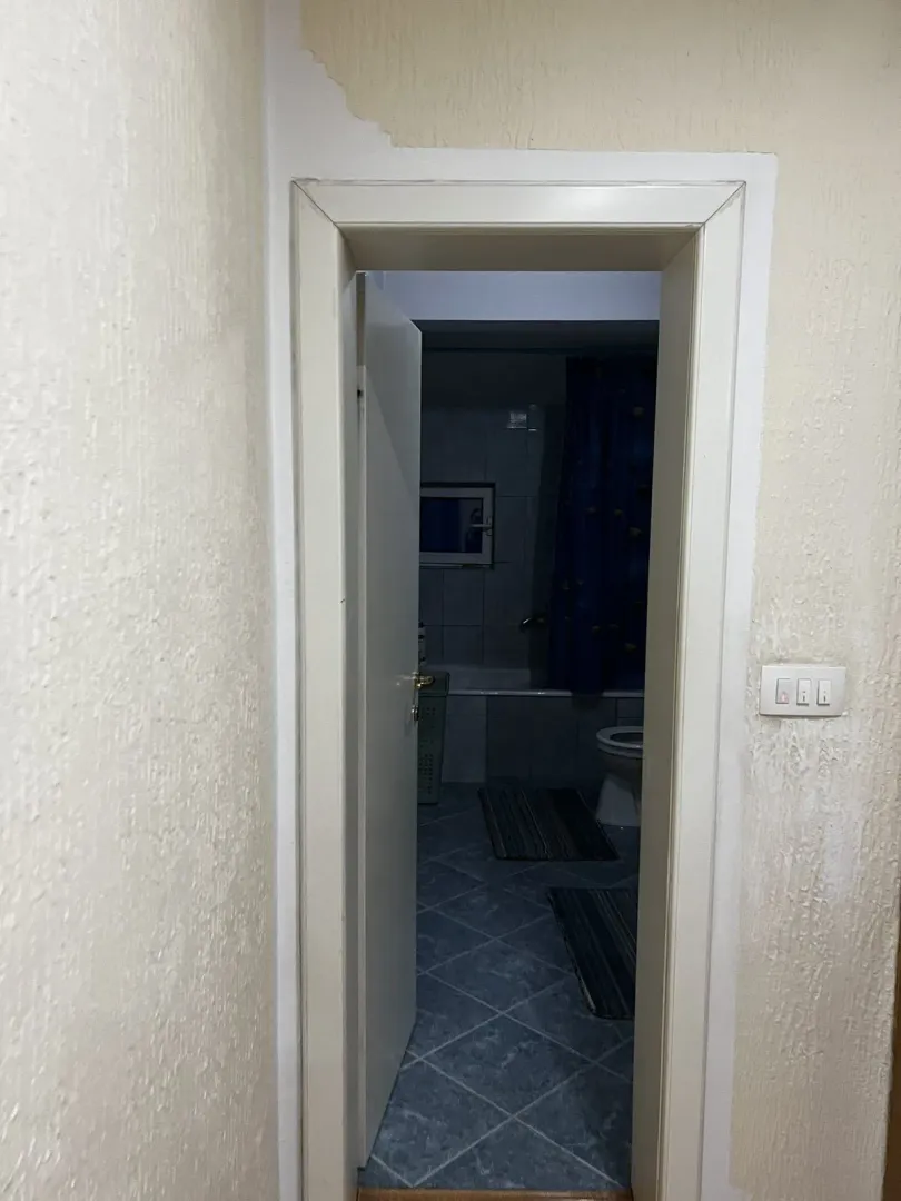 Pogled kroz vrata na funkcionalno kupatilo sa plavim pločicama.