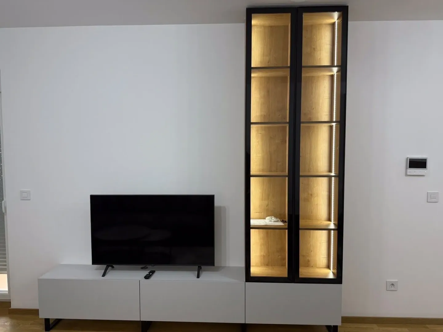 Living room with a television and an illuminated display cabinet.