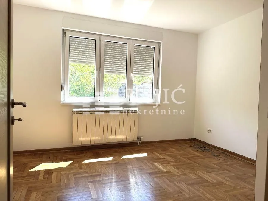Empty room with parquet flooring and a window.