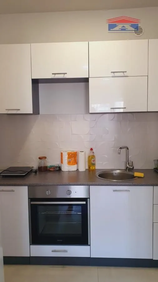 Small kitchen with white cabinets, built-in oven, and sink.