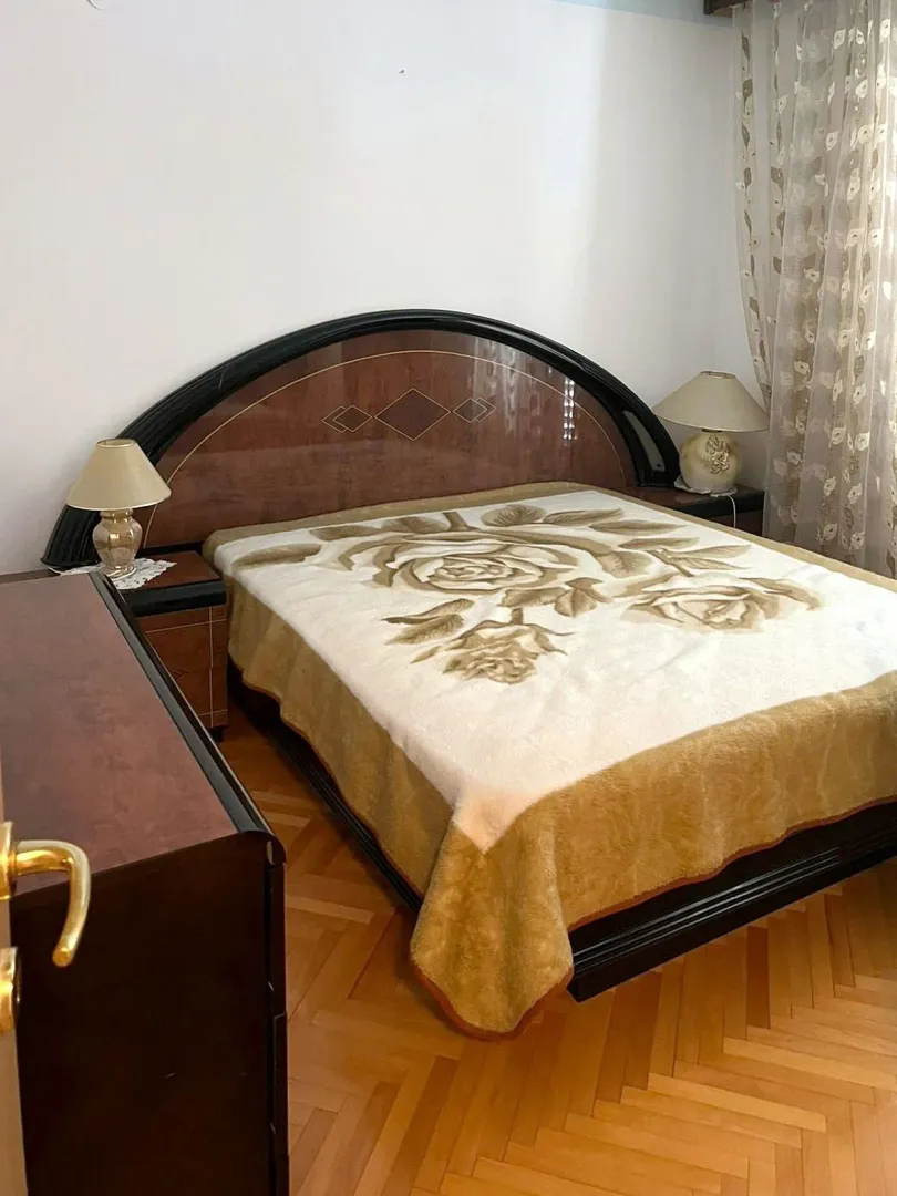 Namještena spavaća soba sa velikim bračnim krevetom i noćnim stočićima.
