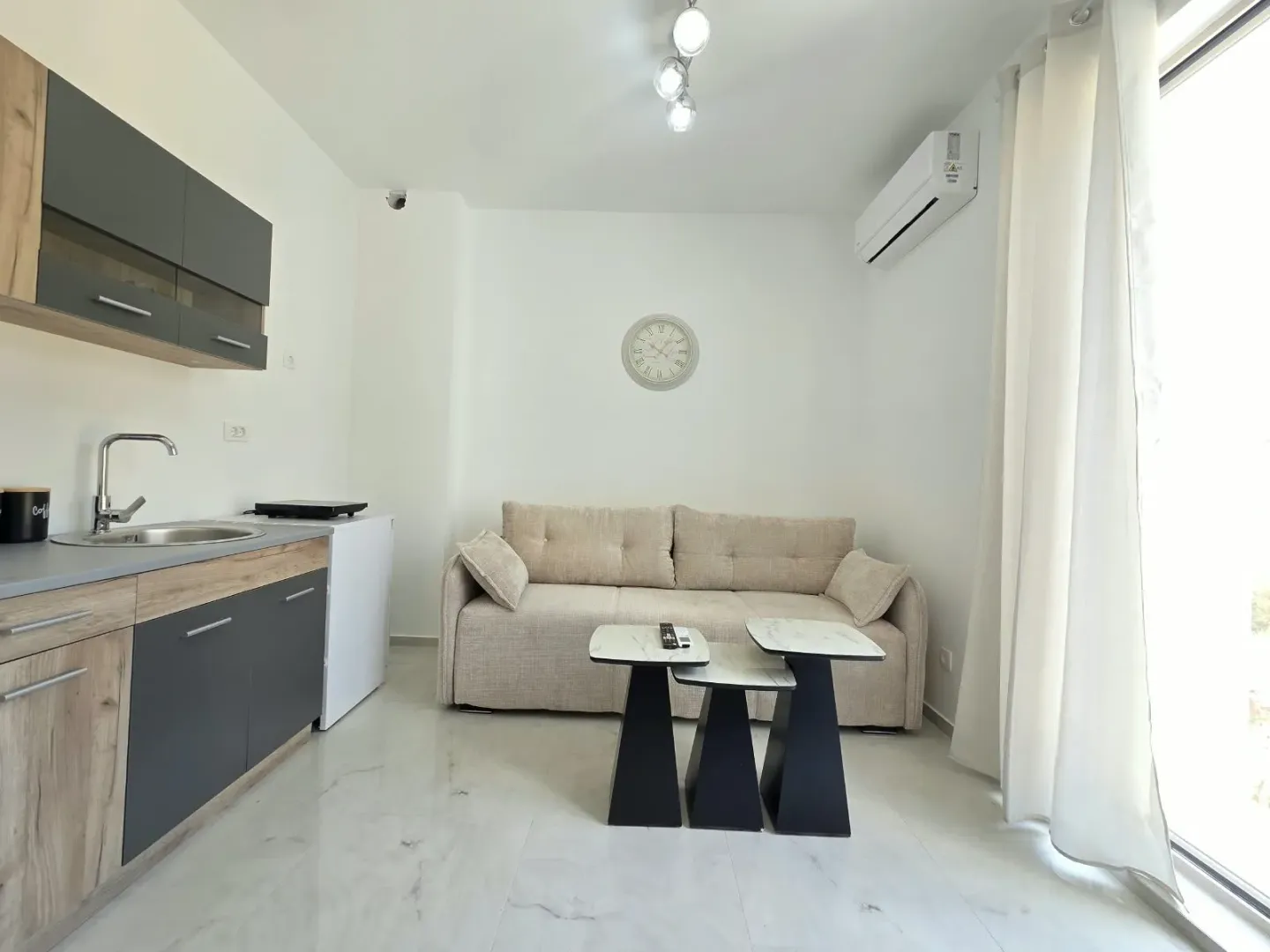 Living room with a sofa, coffee table, and a small kitchen.