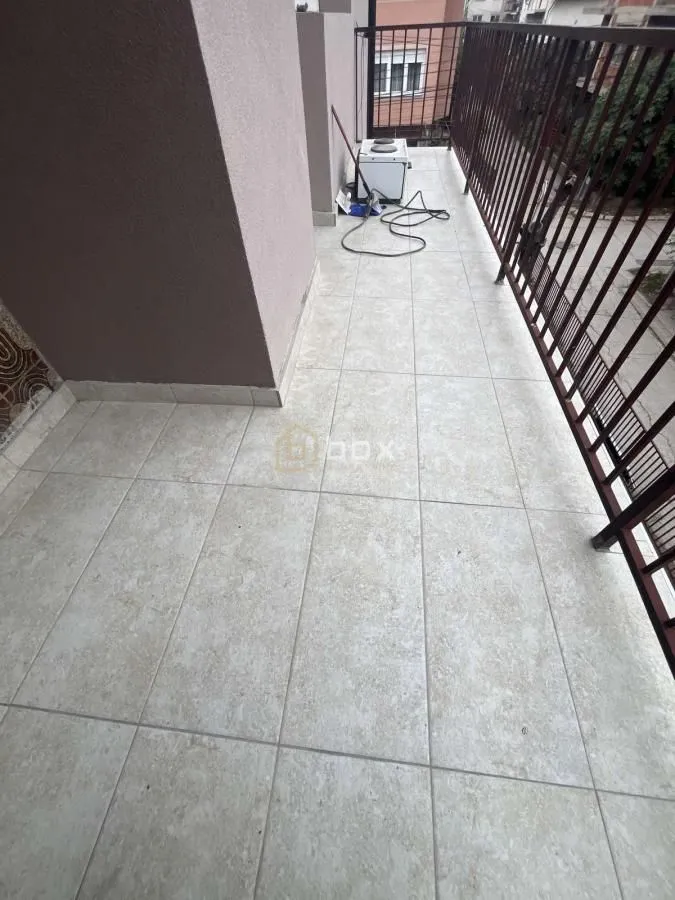 Long tiled balcony with metal railing and an outdoor air conditioning unit.