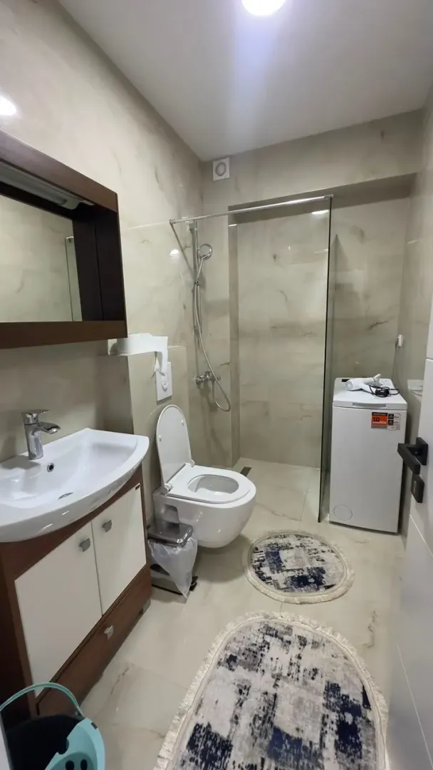 Moderne kupatilo sa umivaonikom, wc šoljom, tuš kabinom i veš mašinom.