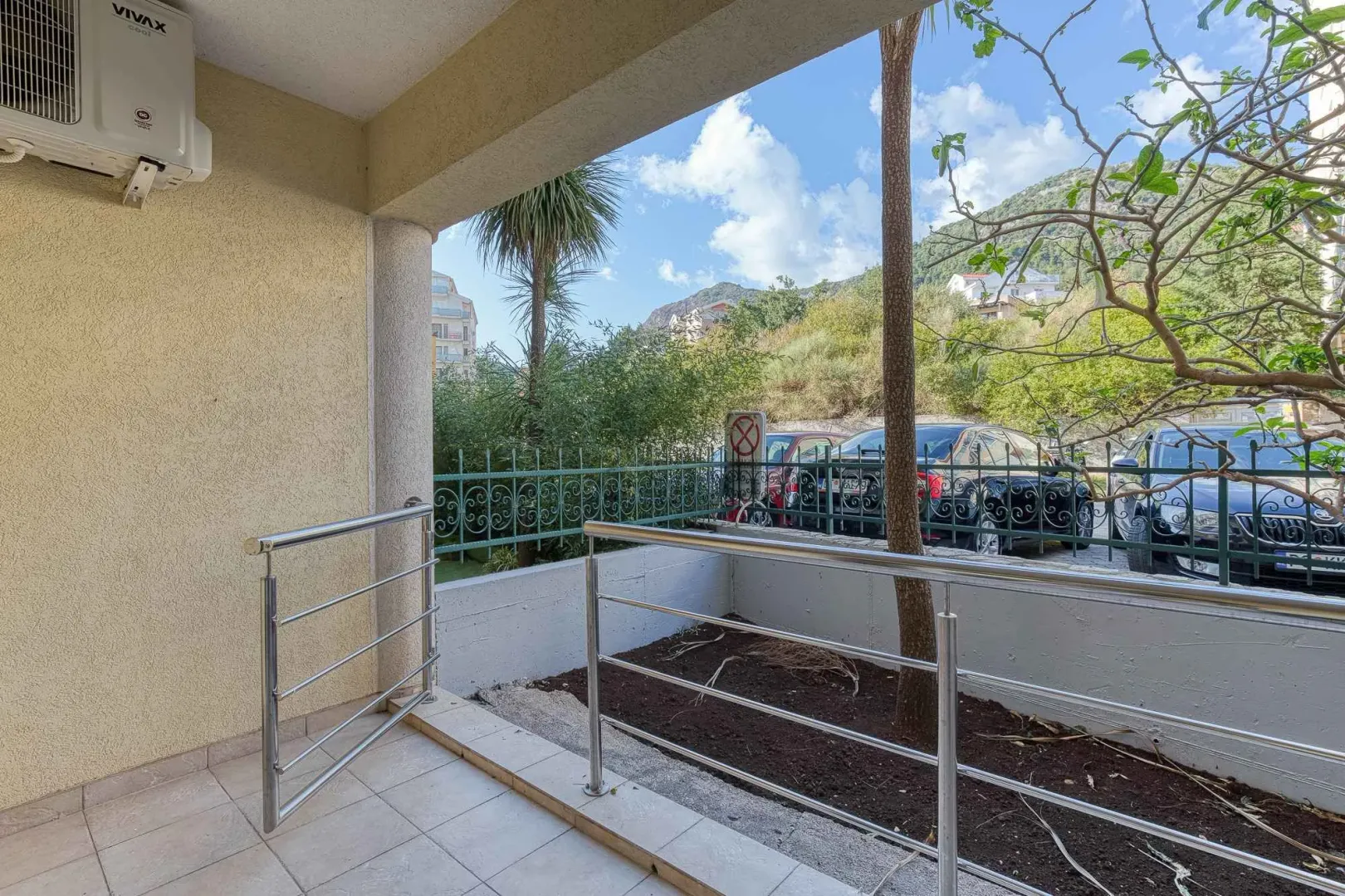 Covered terrace with a metal railing and a view of the courtyard and greenery.