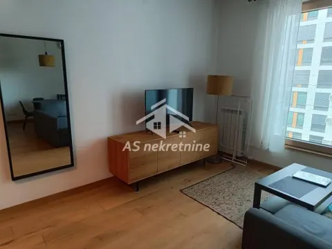 Dnevna soba sa drvenom komodom, TV-om i ogledalom na zidu. - image 3
