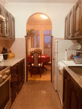 Kitchen with wooden cabinets looking into a dining area through an archway. - image 6