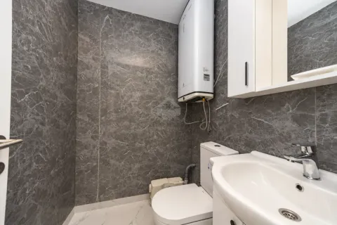 Small bathroom lined with grey marble tiles featuring a washbasin and toilet. - image 8